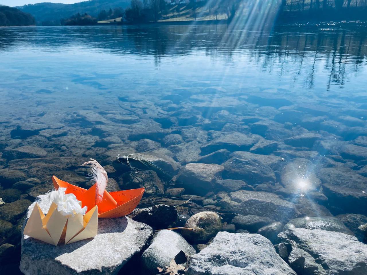 Persönliches Ritual am Rhein mit Origamischiffen